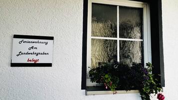 A window with a white frame and a sign on the wall to the left.