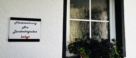 A window with a white frame and a sign on the wall to the left.