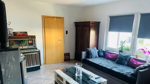 A living room with a sofa, a coffee table, a piano, and a cabinet. - Ferienwohnung "Am Landwehrgraben" (Michelau in Oberfranken)