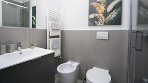 A modern bathroom with a sink, bidet, toilet, and a shower area. - Charming & Modern 3br apt in the Heart of Asti (Asti)