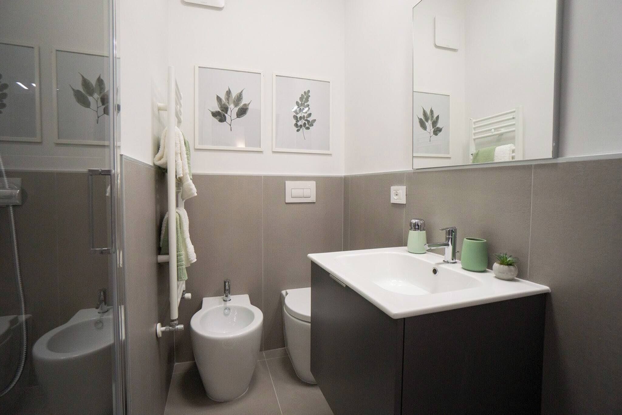 Une salle de bain moderne équipée d’une douche, d’un bidet, de toilettes et d’un lavabo avec un miroir.