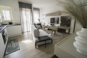 A modern living room with a sofa, coffee table, and a dining area with a table and chairs. - Charming & Modern 3br apt in the Heart of Asti (Asti)