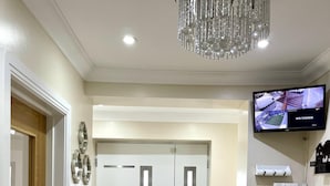 A modern hotel lobby with a chandelier, a security monitor, and a double door with a mat. - New Luxury Modern House Near Airport Free Parking (Luton)