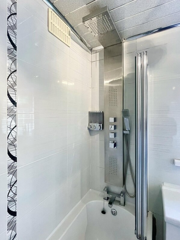 A modern bathroom with a glass-enclosed shower, a separate bathtub, and a toilet.