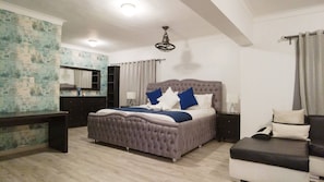 Une chambre à coucher avec un grand lit, un bureau, une commode et une coiffeuse avec un miroir.