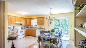 A kitchen with wooden cabinets, a dining table with chairs, and a chandelier.