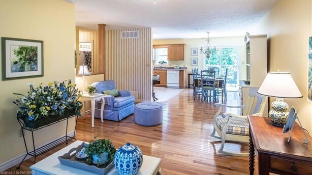 A spacious living room with a sofa, ottoman, and a dining area with chairs and a table.