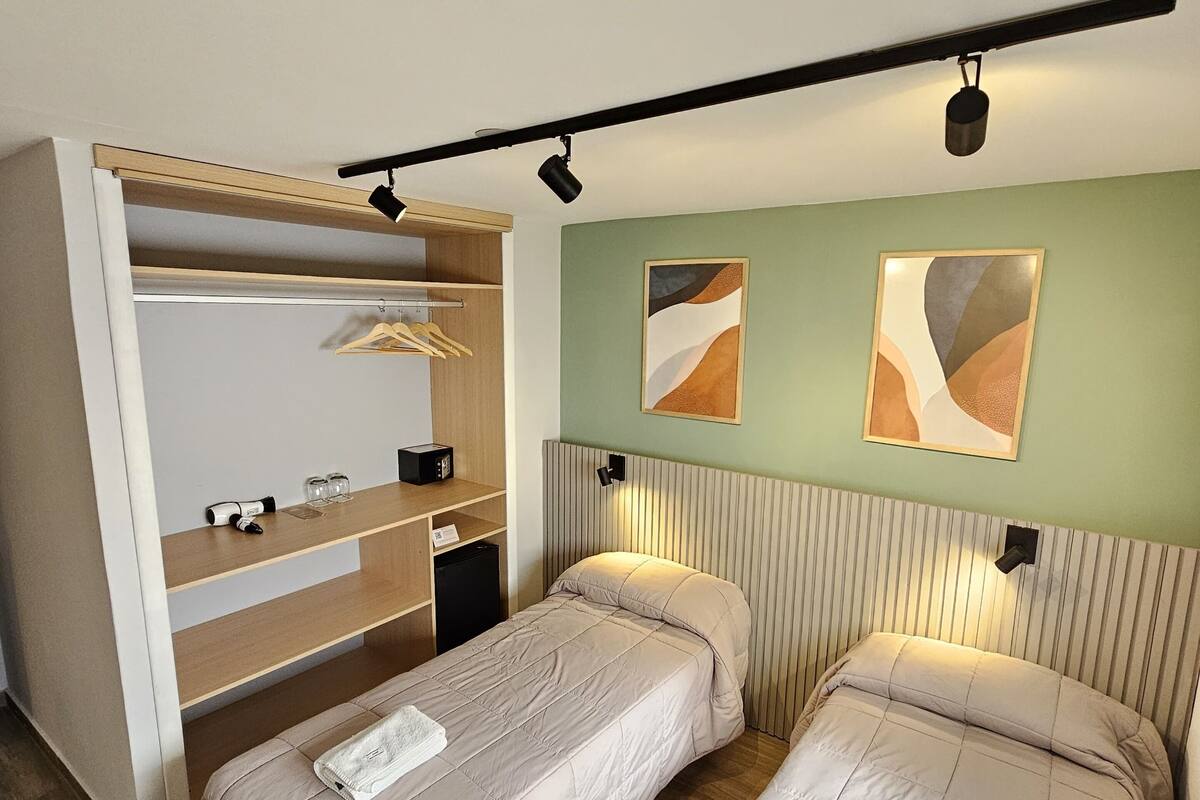 A bedroom with two beds, a built-in wardrobe, and artwork on the wall.