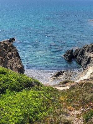 A coastal landscape with rocky cliffs and a clear blue sea.