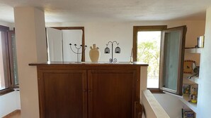 Une cuisine avec des meubles de rangement en bois, une petite chaise et une fenêtre qui laisse entrer la lumière naturelle.