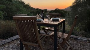 Une table en bois, dressée pour deux personnes, avec vue sur le coucher du soleil.