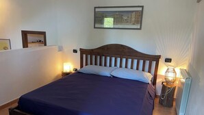 Une chambre à coucher avec un lit en bois, deux lampes de chevet, un radiateur et un tableau encadré accroché au mur.