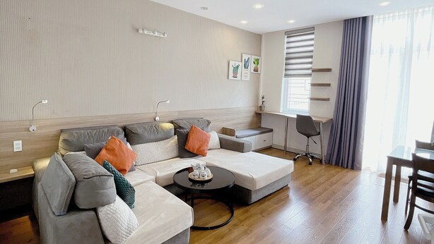 A modern living room with a sectional sofa, a small coffee table, and a dining area with a table and chairs. - Phu My An Apartment Hue (Hue)