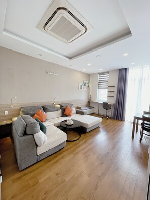 Ein modernes Wohnzimmer mit einem Ecksofa, einem kleinen Couchtisch und einem Essbereich mit Tisch und Stühlen.