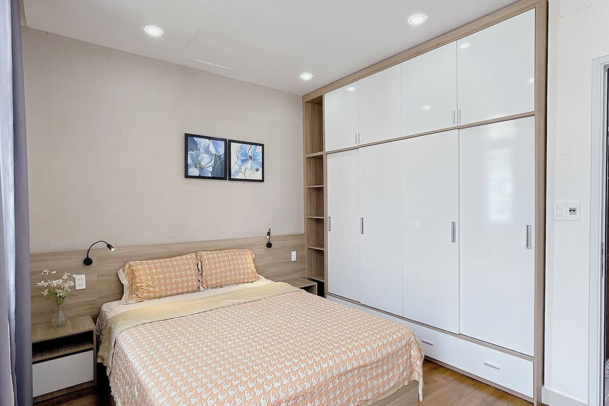 A bedroom with a bed, wardrobe, and a nightstand with a lamp.