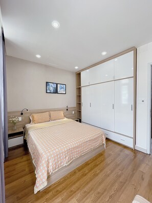 A bedroom with a bed, wardrobe, and a nightstand with a lamp. - Amy Phu My An Apartment Hue (Hue)