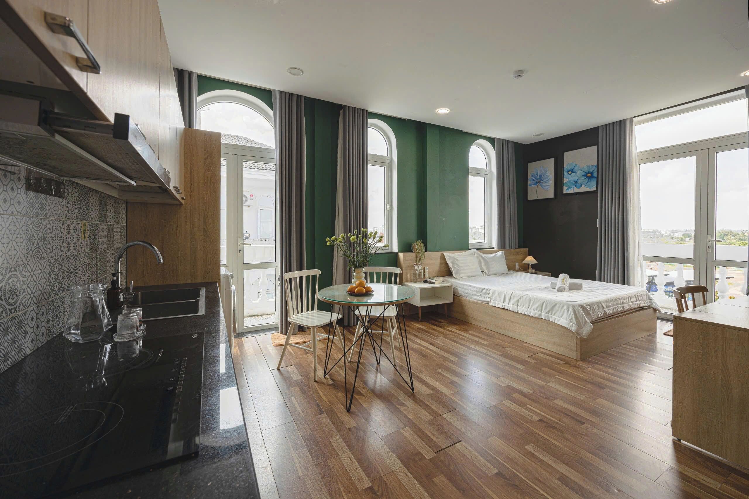 Une chambre d’hôtel compacte comprenant un coin cuisine, un espace repas, un lit et de grandes fenêtres.