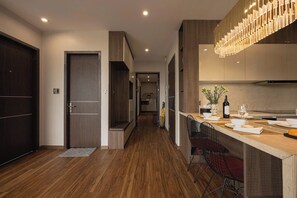 A modern kitchen with a wooden countertop, bar seating, and a hanging light fixture. - Amy Phu My An Apartment Hue (Hue)