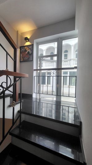 A staircase with a black railing leading to a balcony with a glass door. - Amy Apartment Hue (Hue)