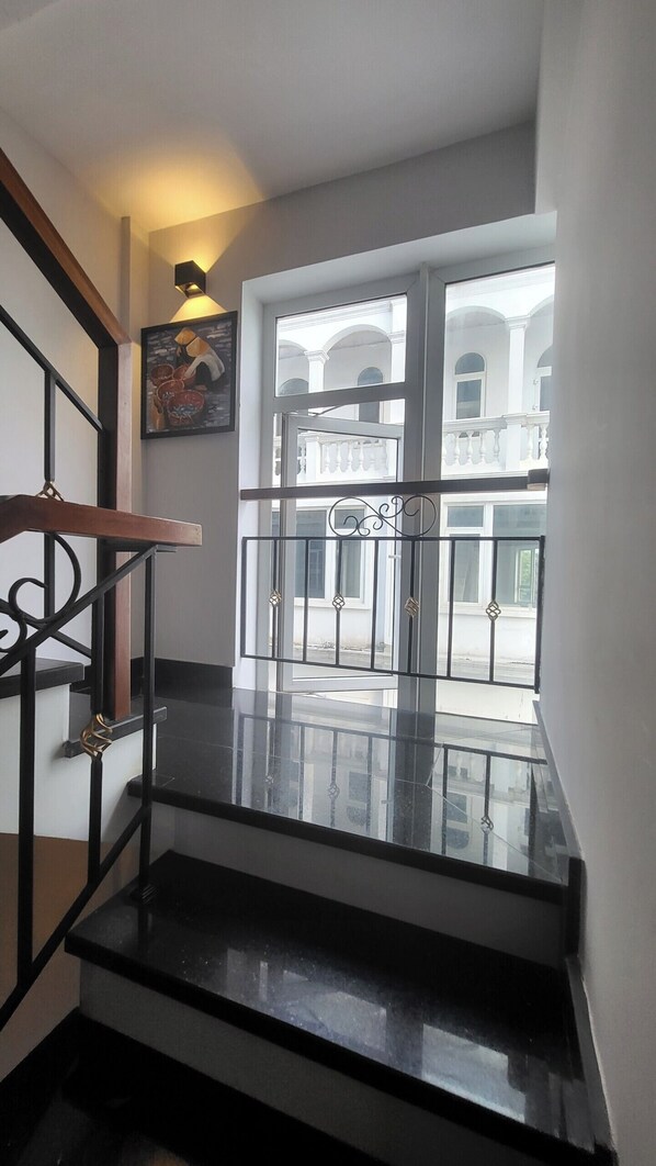 A staircase with a black railing leading to a balcony with a glass door. - Amy Apartment Hue (Hue)