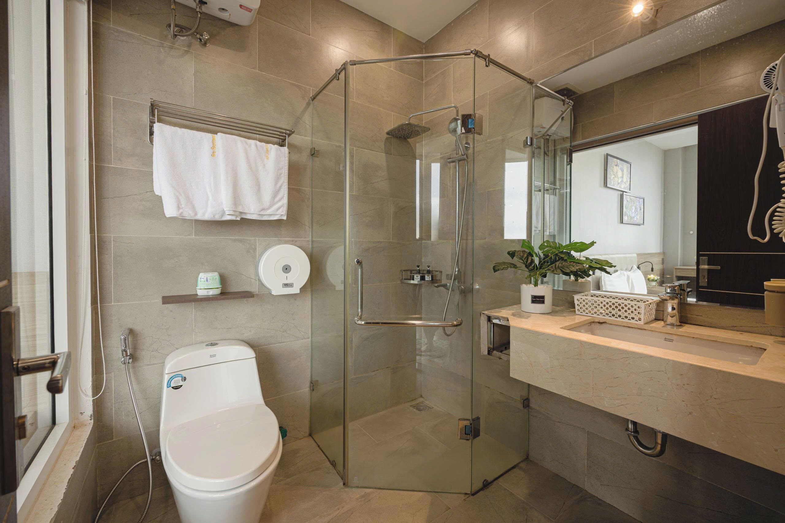 A modern bathroom with a glass-enclosed shower, a toilet, a sink with a mirror, and a towel rack.