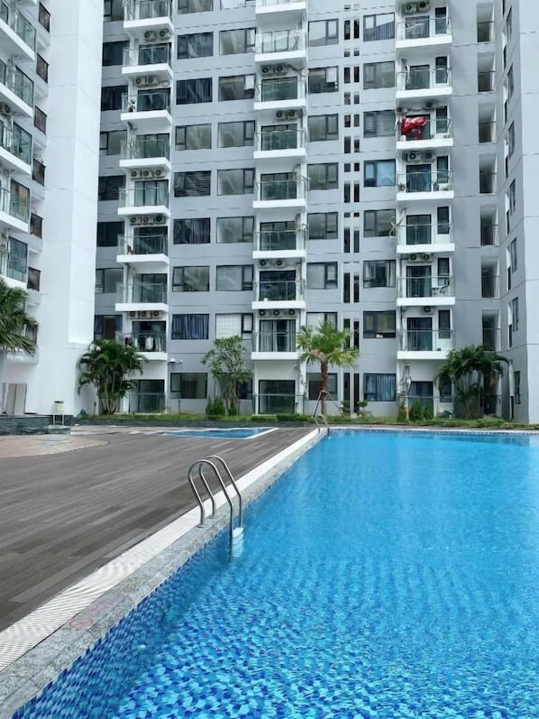 A modern multi-story residential building with a swimming pool in the foreground. - Amy Apartment Hue (Hue)