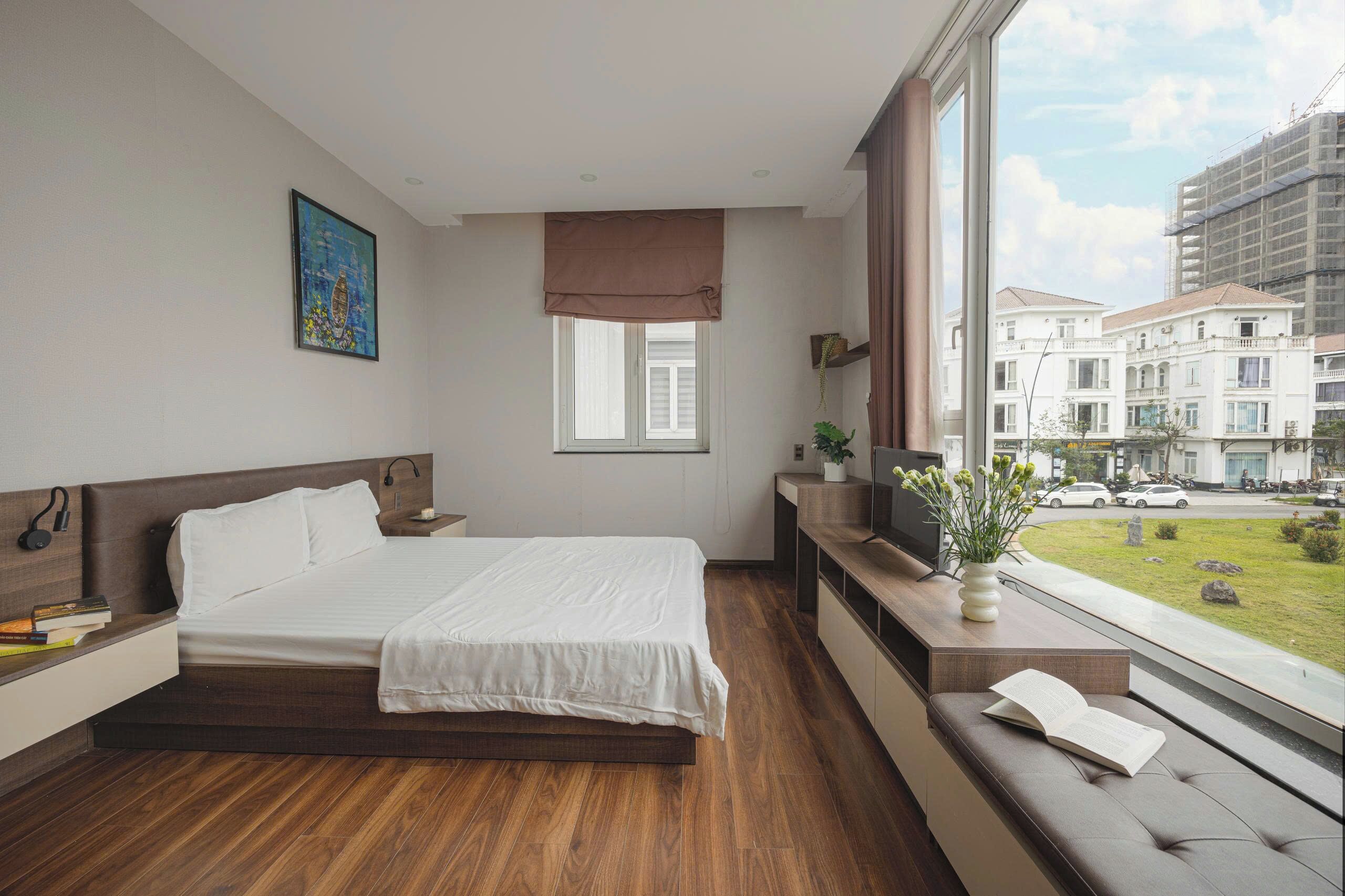 Ein Hotelzimmer mit einem großen Bett, Nachttischen, einem Fernseher und Blick auf die Stadt.
