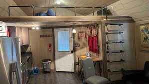 Ein kleines Zimmer mit Etagenbett, Küchenzeile und einer kleinen Essecke.