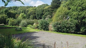 Ein Kiesparkplatz mit Picknicktisch und Bänken, umgeben von üppigem Grün und Bäumen.