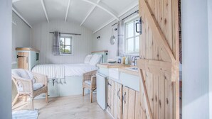 Une chambre confortable avec un lit, deux fauteuils en osier, une petite fenêtre et une armoire en bois.