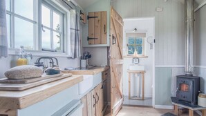 Une cuisine avec des meubles en bois, une grande fenêtre, un évier et un poêle à bois.