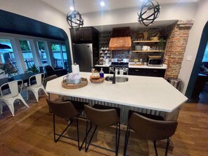 Une cuisine moderne dotée d’un grand îlot central, de tabourets de bar, d’un réfrigérateur, d’une cuisinière et d’un four à micro-ondes.