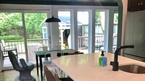 A kitchen with a large island, bar stools, and a hanging light fixture. - Binghamton's Beautiful Riverside Drive Living!
 (Binghamton)