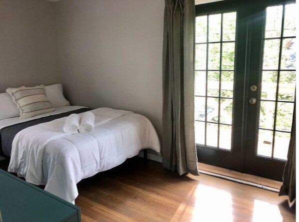 Une chambre à coucher avec un lit, une fenêtre avec des rideaux et une vue sur la verdure.