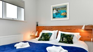 Una habitación de hotel con una cama grande, cabecero de madera, una ventana y un cuadro enmarcado con una escena de piscina.