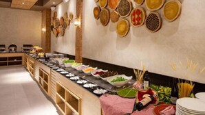 A buffet setup with various food items and a wall decorated with patterned plates. - Ondas Praia Resort - MC (Porto Seguro)