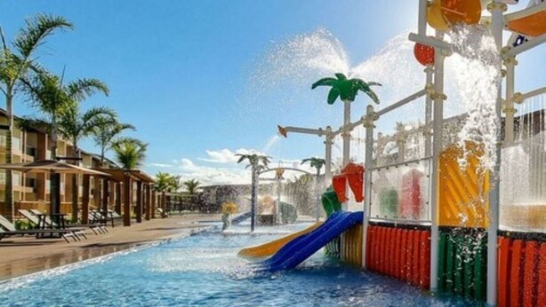 A swimming pool with a water slide and a palm tree-lined deck. - Ondas Praia Resort - MC (Porto Seguro)