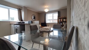 Una cocina moderna con lavadora, una mesa de comedor con sillas y una estantería.