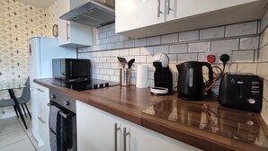 Una cocina con microondas, cafetera, hervidor, tostadora y un portalápices en la encimera.
