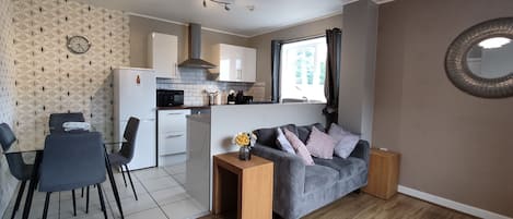 A compact living space with a kitchenette, a dining area, and a seating area with a sofa and a small table.
