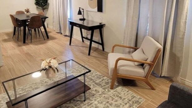 Ein Wohnzimmer mit Essbereich, einem Couchtisch, einem Sessel und einer Zimmerpflanze.