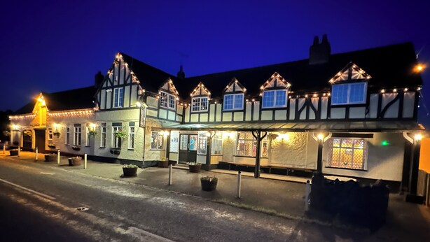 A traditional building with multiple windows and a covered entrance area, likely a hotel or pub.