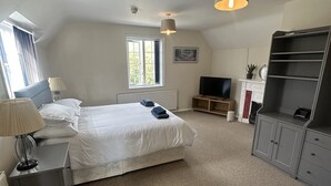 A bedroom with a bed, a TV, a desk, and a shelving unit.