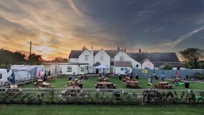 Un terrain de camping avec de nombreuses caravanes, un grand bâtiment blanc doté d’un toit plat et des tables de pique-nique disposées au premier plan.