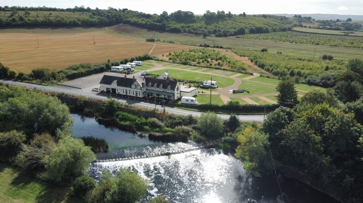 Een hotel aan de rivier met een groot gebouw, een parkeerplaats en een verzorgd gazon.