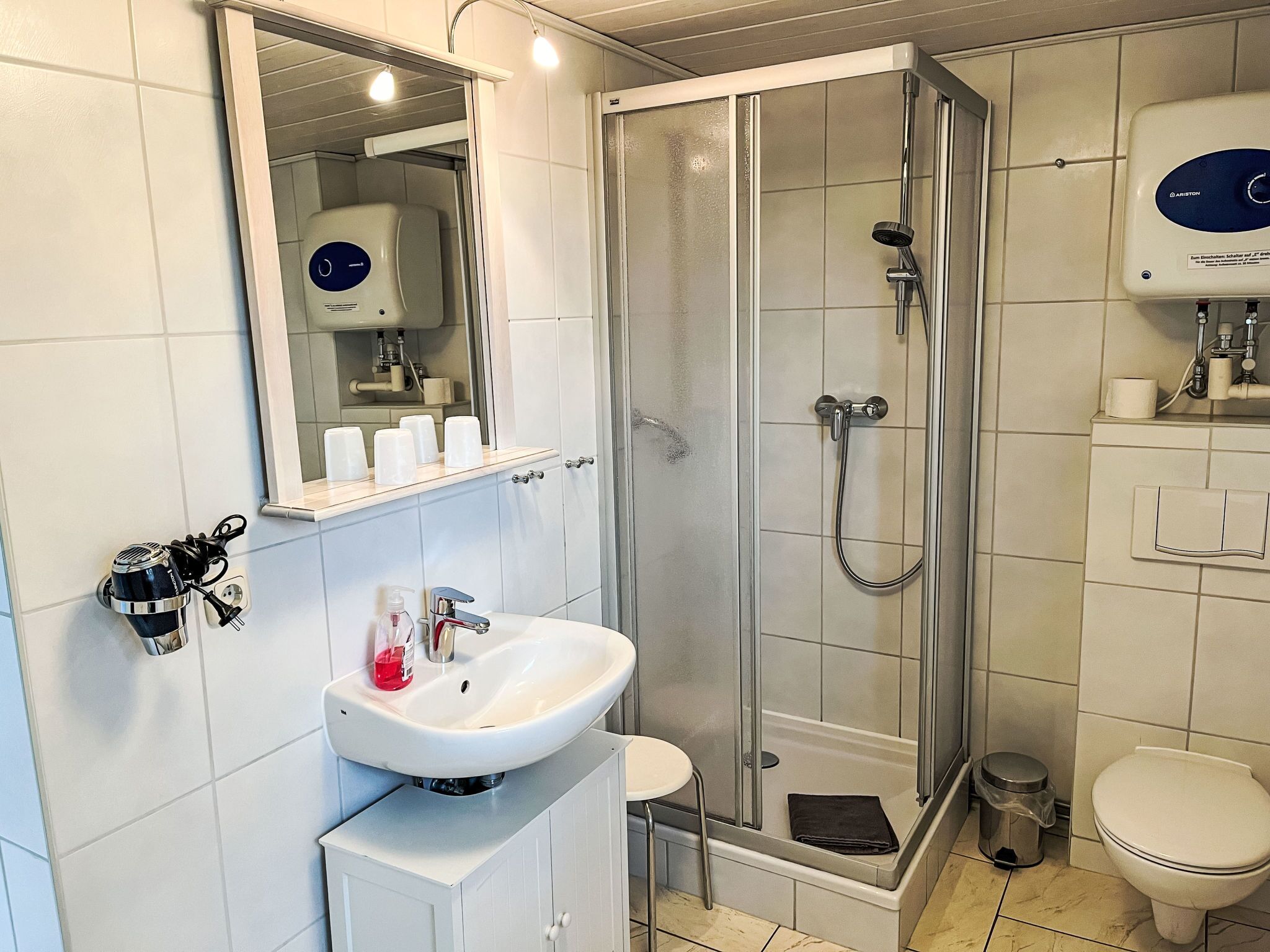 Een moderne badkamer met douche, toilet, wastafel en spiegel.