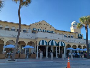 Un edificio con un letrero que dice "Lake Worth Casino" y terraza al aire libre con sombrillas.