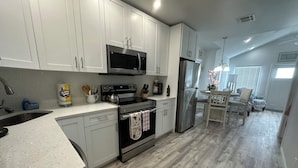 A modern kitchen with white cabinets, stainless steel appliances, and a wooden floor. - Historical Cottage in Downtown Lake Worth Beach, fully renovated and modernized (Lake Worth)