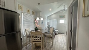 A modern kitchen with a built-in refrigerator, wooden dining table, and chairs. There is a ceiling fan and a dining area with a sofa and a chair. - Historical Cottage in Downtown Lake Worth Beach, fully renovated and modernized (Lake Worth)