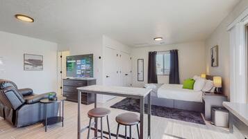Habitació d'hotel moderna amb llit, escriptori, sofà i televisió.